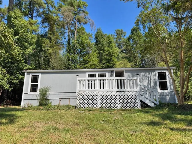 Light gray exterior siding with white trim windows and a white front deck featuring lattice detailing