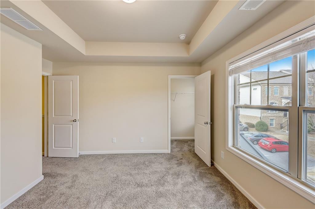 Unfurnished room featuring light colored carpet and a tray ceiling