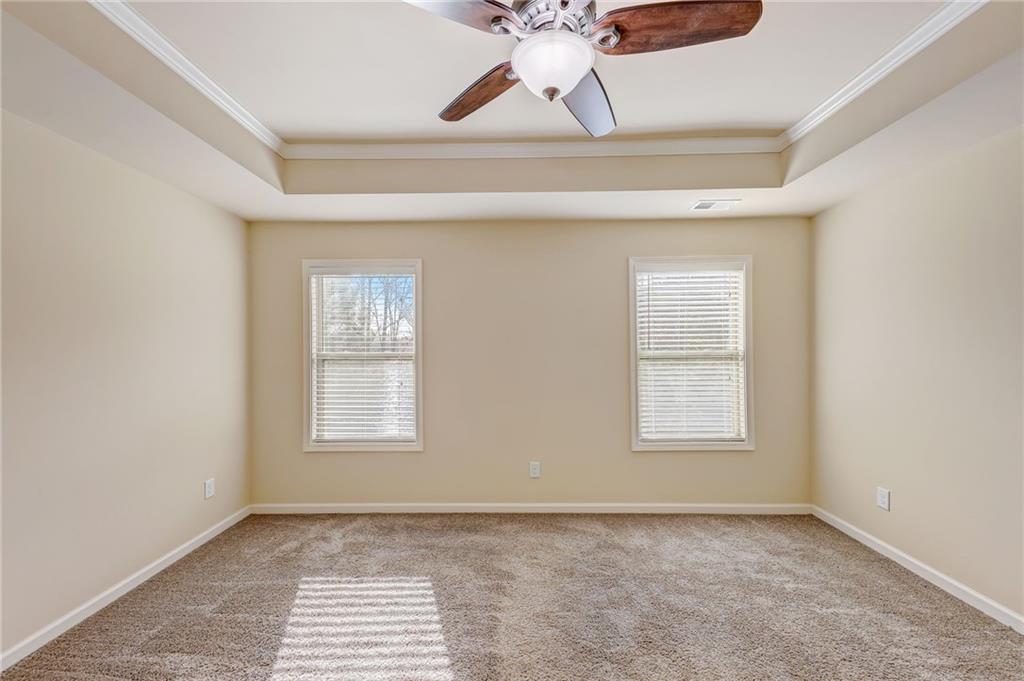 Carpeted empty room with crown molding, a tray ceiling, and ceiling fan