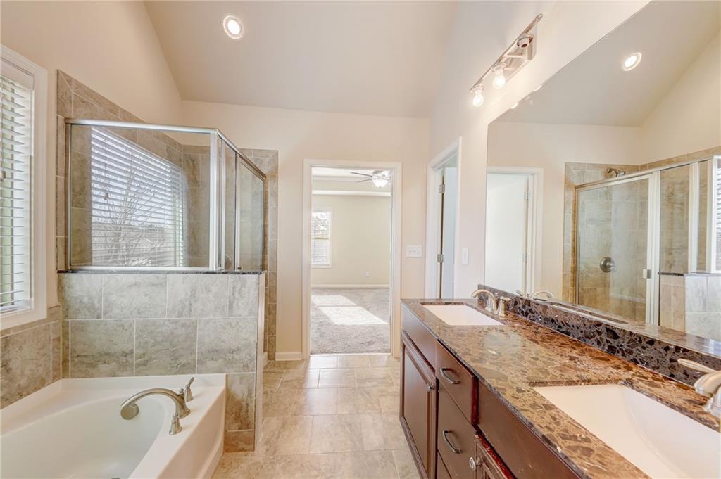 Bathroom with tile floors, plenty of natural light, separate shower and tub, and dual sinks