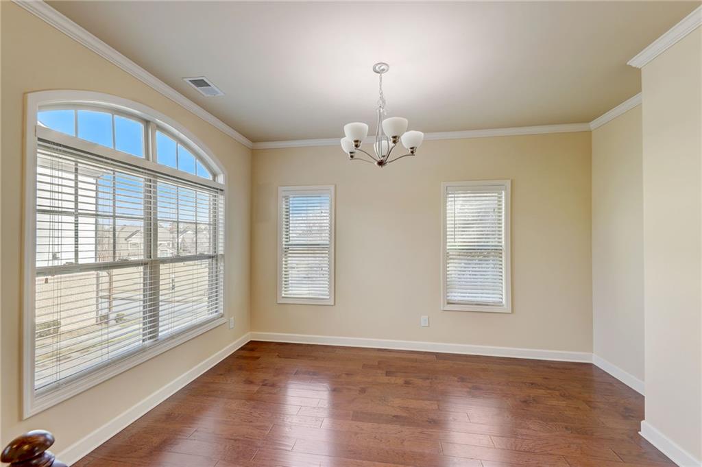 Unfurnished room with an inviting chandelier, dark hardwood / wood-style floors, and a healthy amount of sunlight