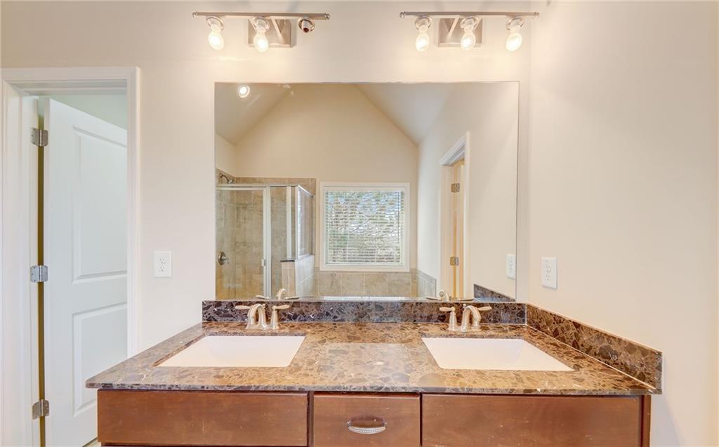 Bathroom with a shower with shower door, vaulted ceiling, and double sink vanity