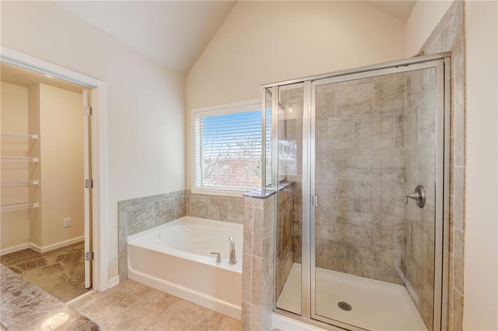 Bathroom featuring lofted ceiling, independent shower and bath, and tile flooring