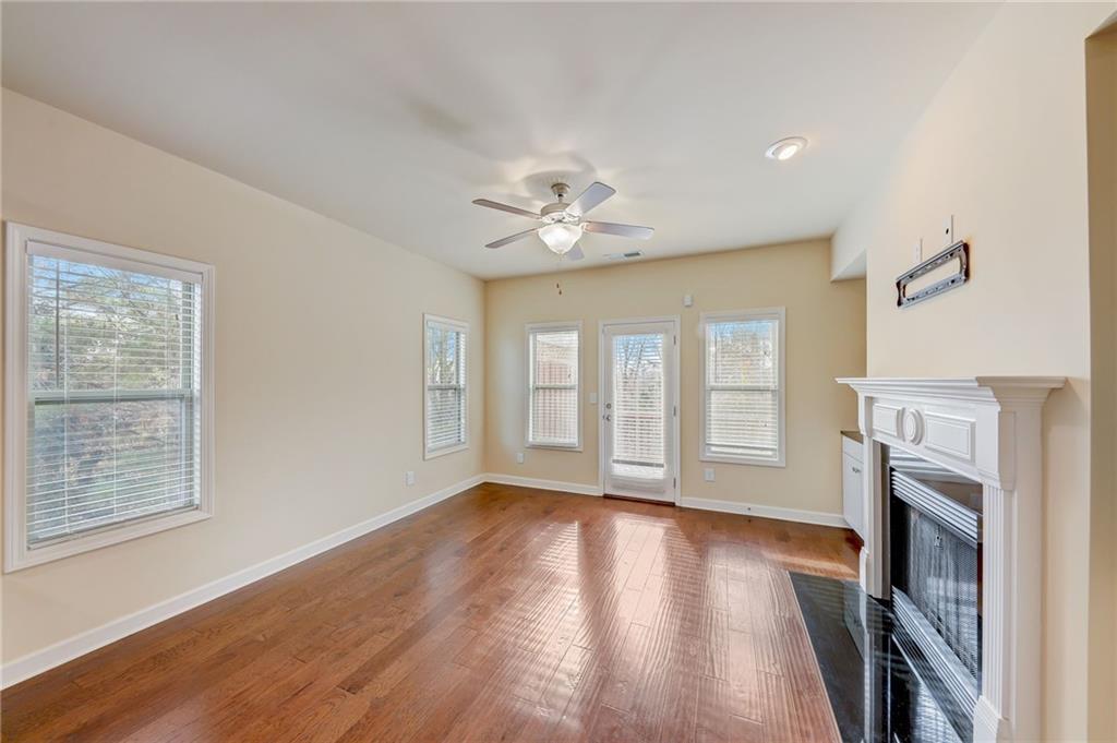 Unfurnished living room featuring plenty of natural light, dark wood-type flooring, and ceiling fan