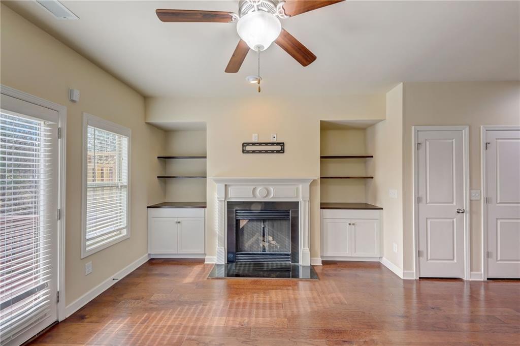 Unfurnished living room with dark hardwood / wood-style flooring, built in features, and ceiling fan