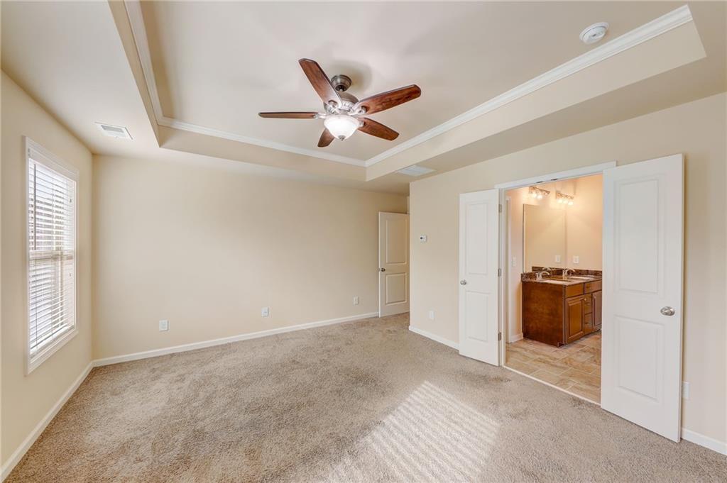 Spare room featuring sink, light colored carpet, ceiling fan, and a raised ceiling