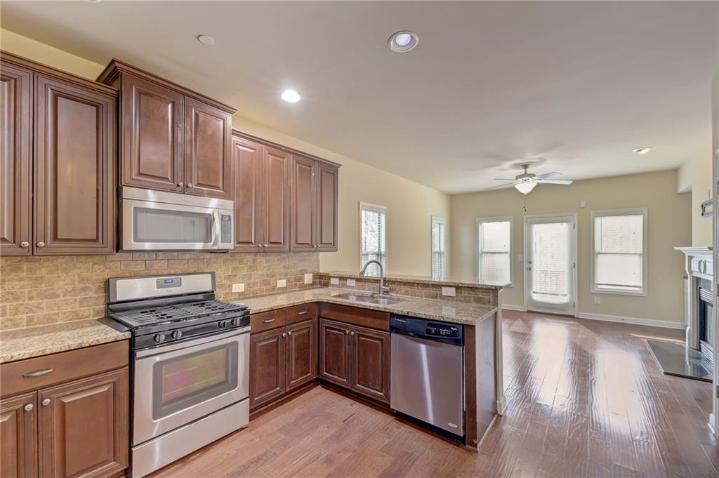 Kitchen with kitchen peninsula, stainless steel appliances, ceiling fan, sink, and light wood-type flooring