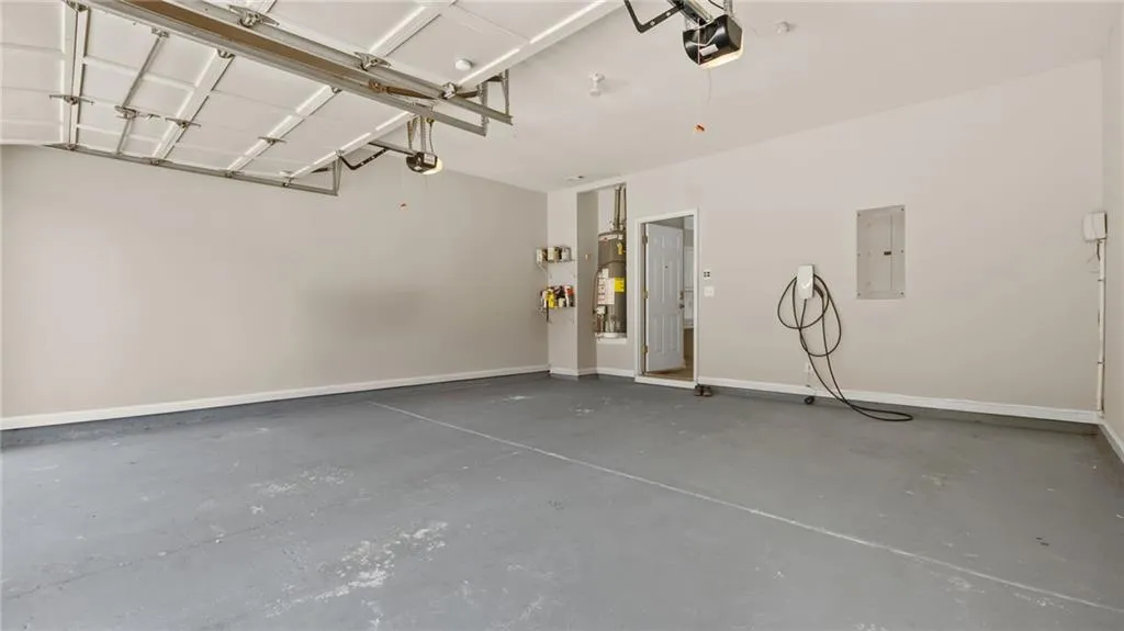 Garage with electric panel, a garage door opener, and baseboards
