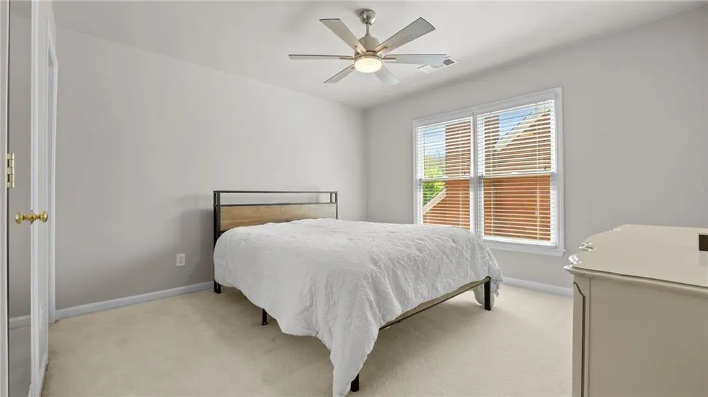 Bedroom with light colored carpet, ceiling fan, and baseboards