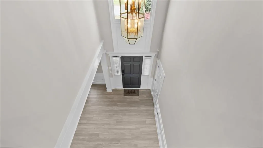Entryway featuring baseboards, a towering ceiling, light wood-style flooring, and a notable chandelier