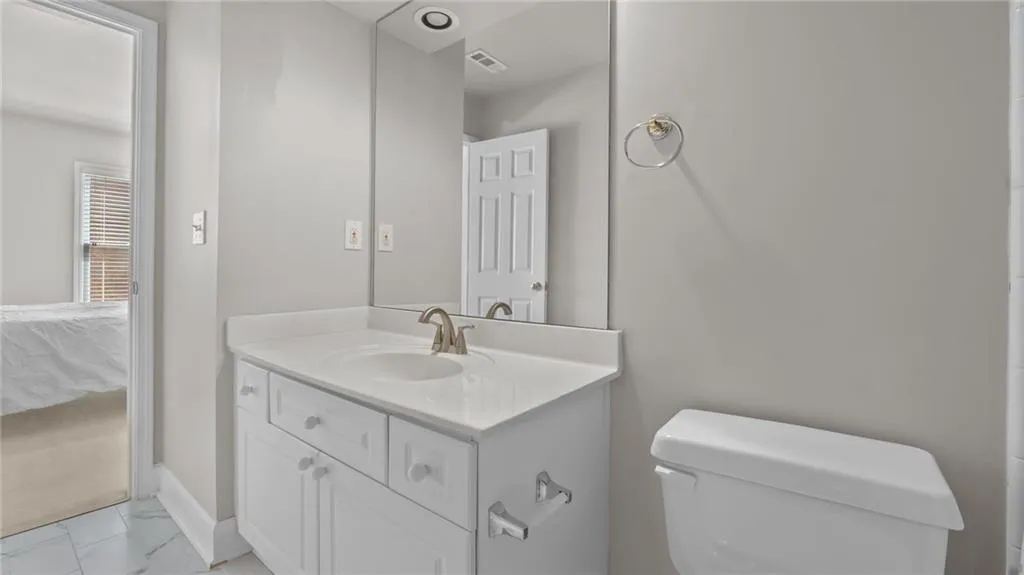 Bathroom featuring marble finish floor, visible vents, toilet, and vanity