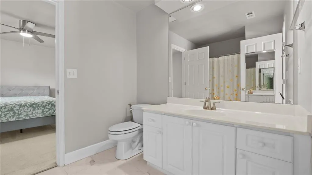 Ensuite bathroom featuring toilet, baseboards, marble finish floor, ceiling fan, and visible vents