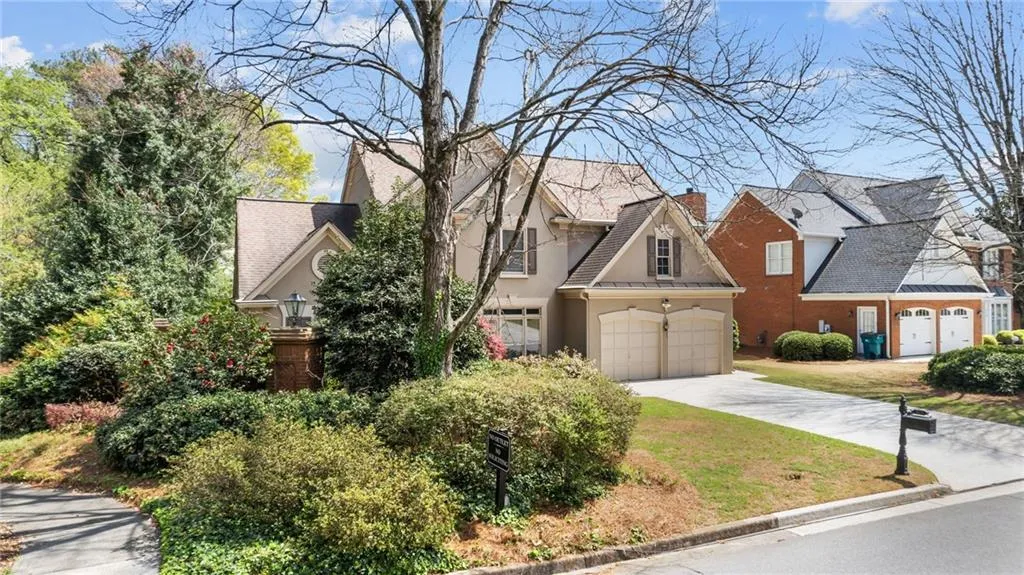 View of front of home with a garage, driveway, stucco siding, and a chimney