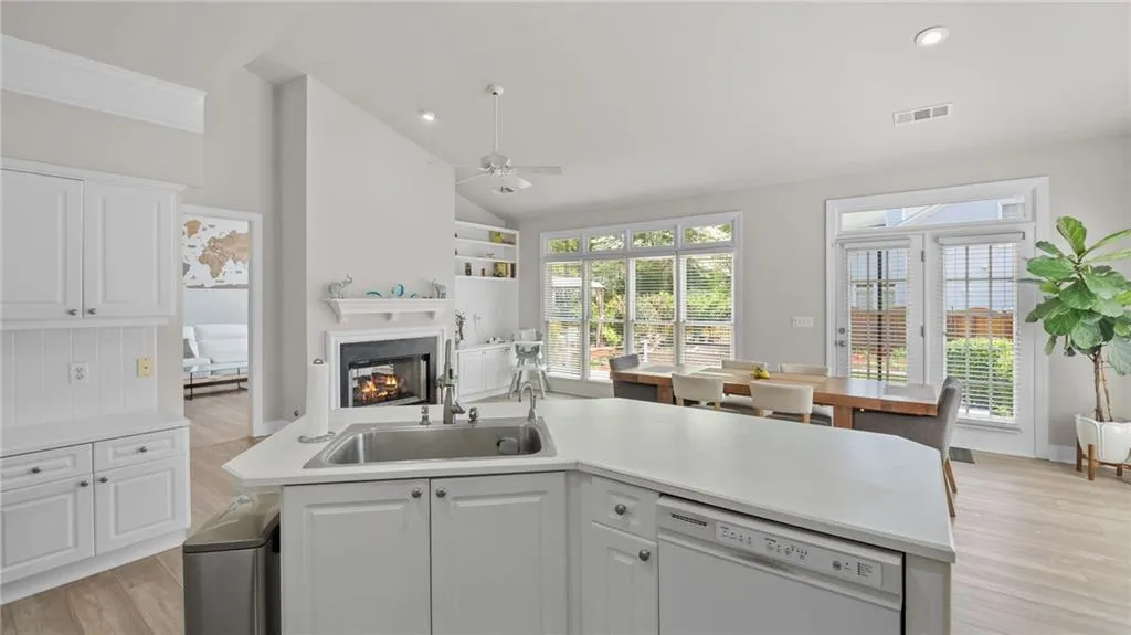Kitchen with white cabinetry, a sink, white dishwasher, and light wood-type flooring