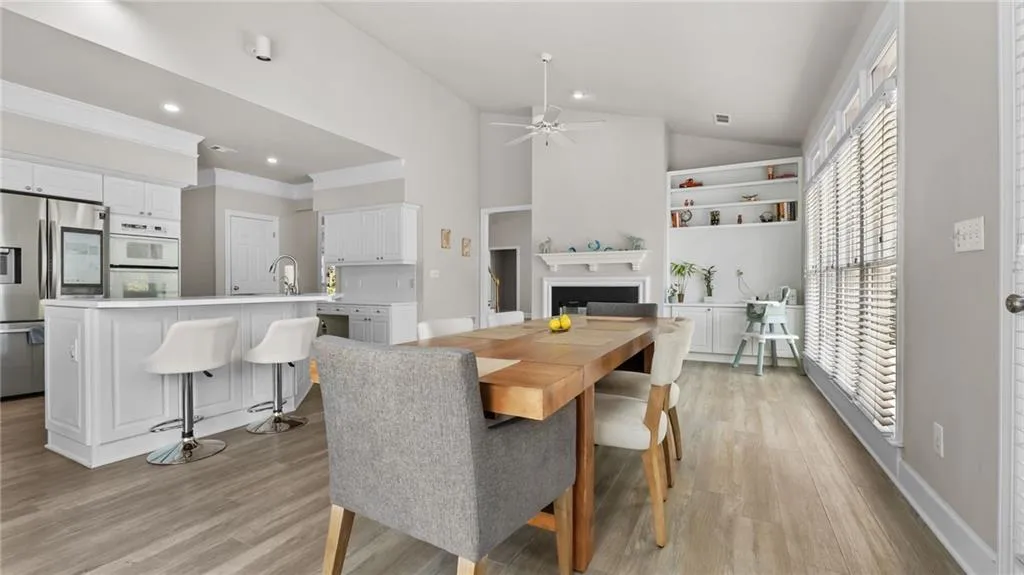 Dining room featuring a ceiling fan, light wood finished floors, a fireplace, lofted ceiling, and recessed lighting