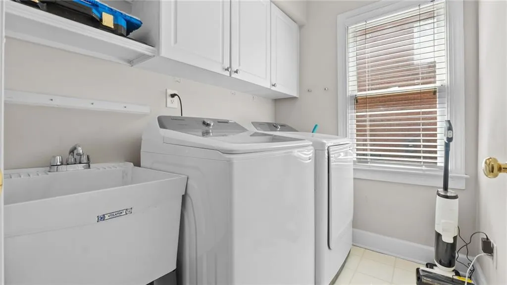 Laundry room featuring washing machine and clothes dryer, a sink, cabinet space, and baseboards
