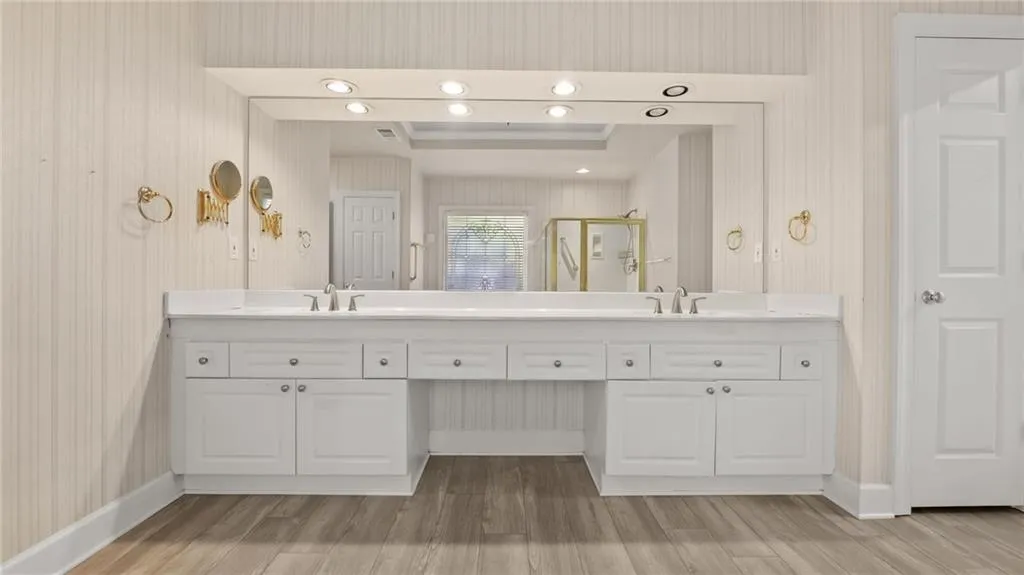 Full bathroom featuring double vanity, a sink, a stall shower, and wood finished floors