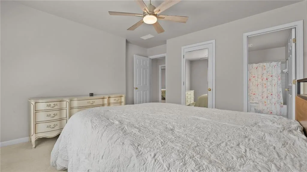 Bedroom featuring light colored carpet, baseboards, and a ceiling fan