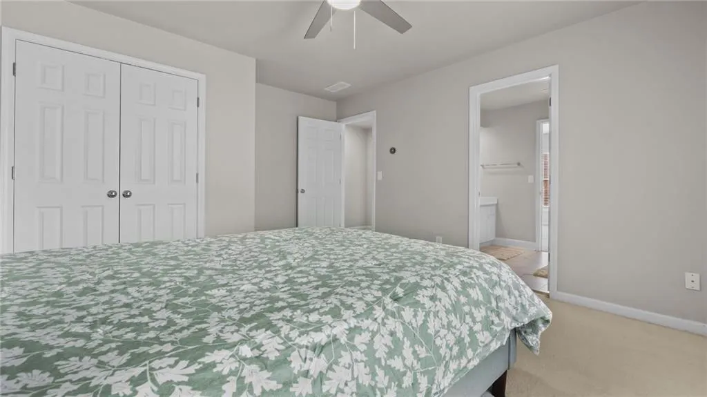 Bedroom featuring light colored carpet, baseboards, connected bathroom, ceiling fan, and a closet