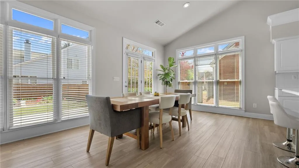 Dining space with light wood-style floors, baseboards, lofted ceiling, and visible vents