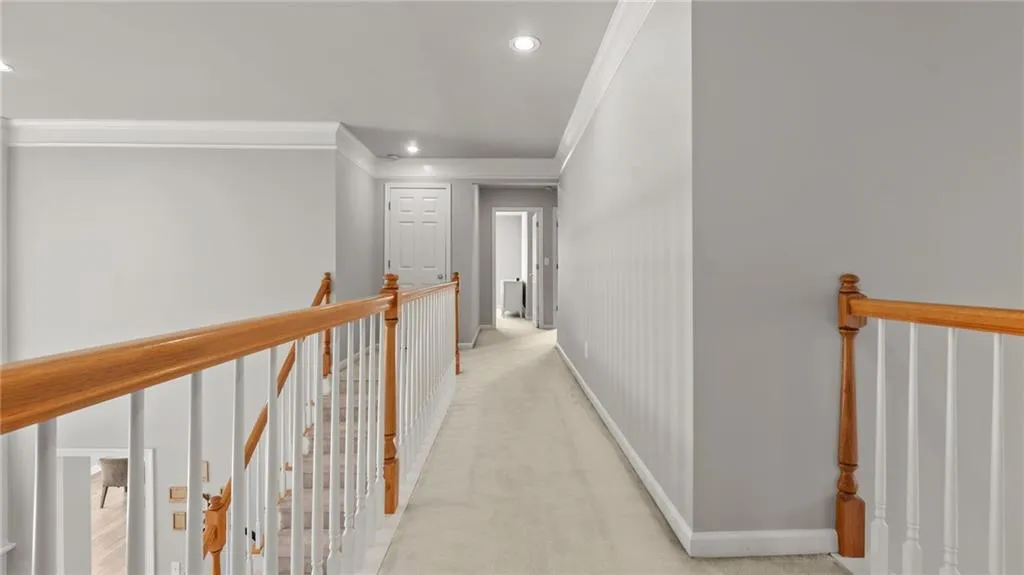 Hallway featuring light carpet, baseboards, and ornamental molding