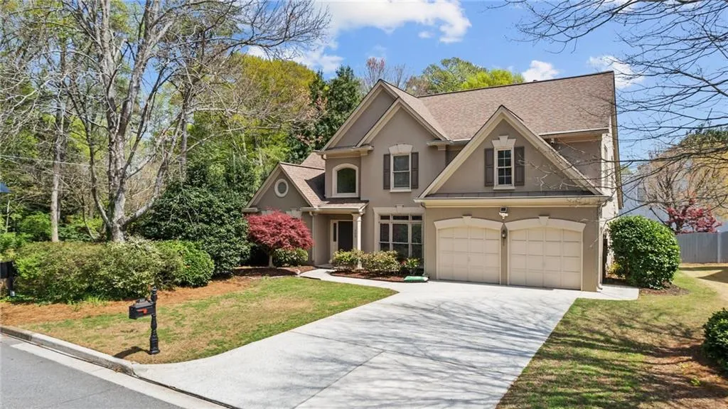 View of front facade featuring driveway, roof with shingles, stucco siding, a front lawn, and a garage