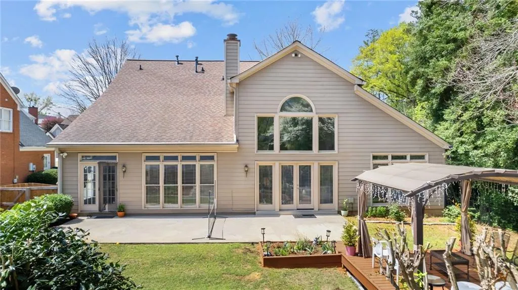 Rear view of house featuring a lawn, a chimney, roof with shingles, and a patio area