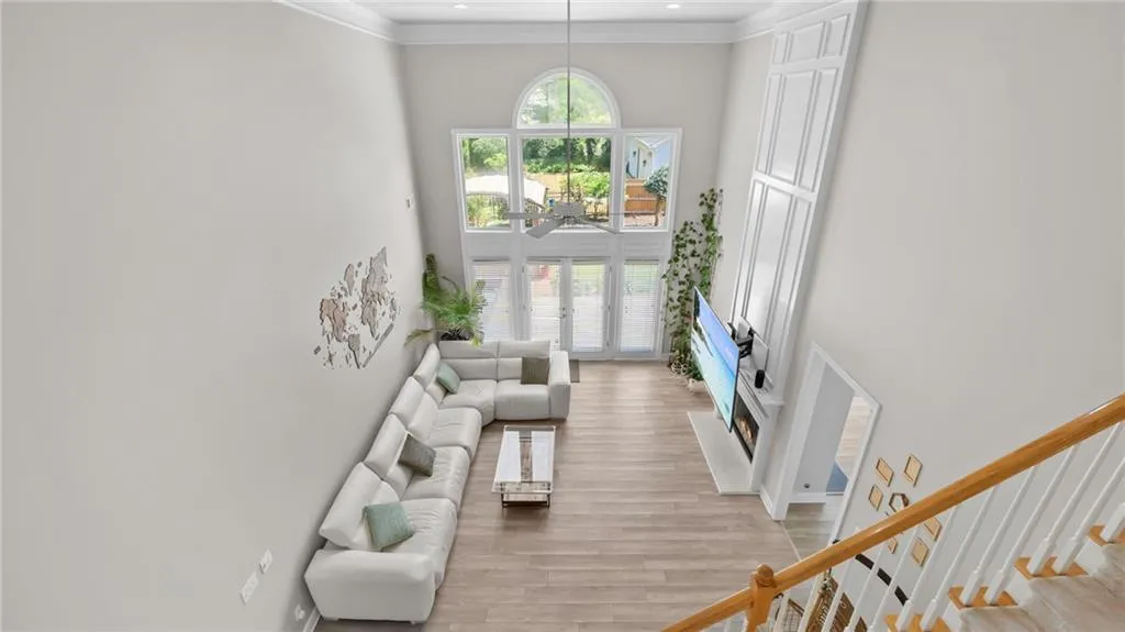 Living area featuring a towering ceiling, crown molding, stairs, and light wood-type flooring