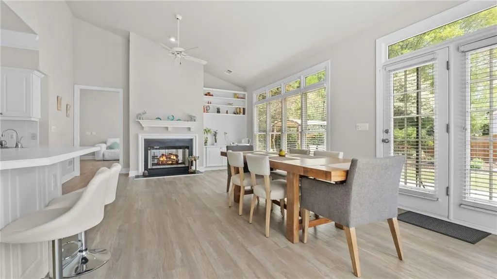 Dining area featuring high vaulted ceiling, light wood-style flooring, a ceiling fan, built in features, and a multi sided fireplace