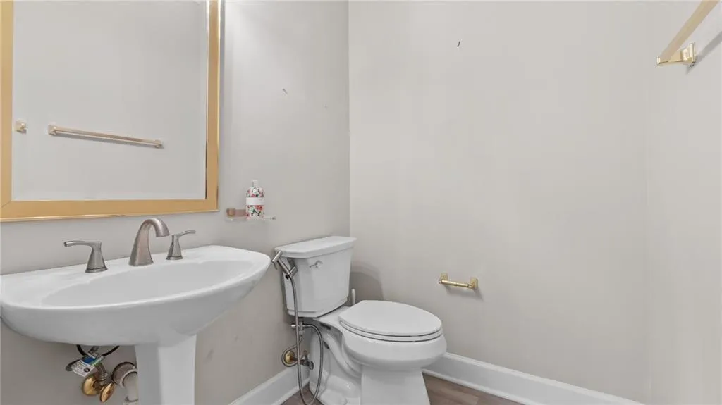 Half bath featuring baseboards, toilet, and a sink