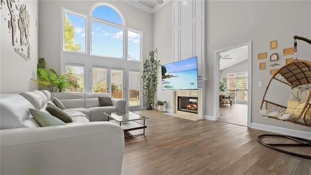 Living room featuring baseboards, wood finished floors, and a towering ceiling
