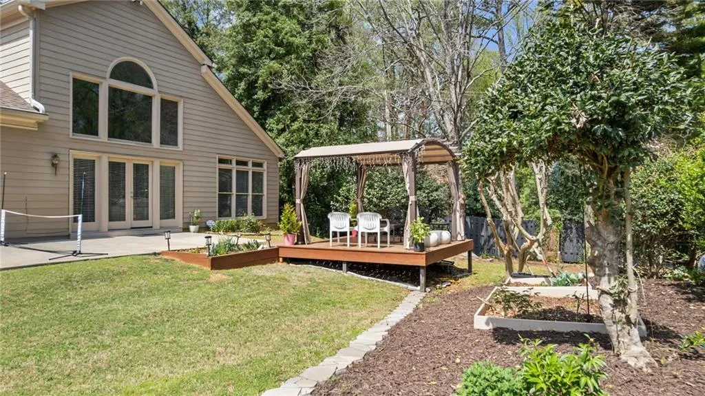 View of yard with a garden, a deck, fence, and a patio area