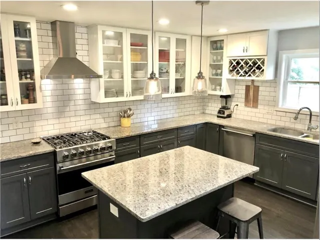 Gourmet kitchen featuring a stainless steel gas range, coordinating range hood, and paneled dishwasher