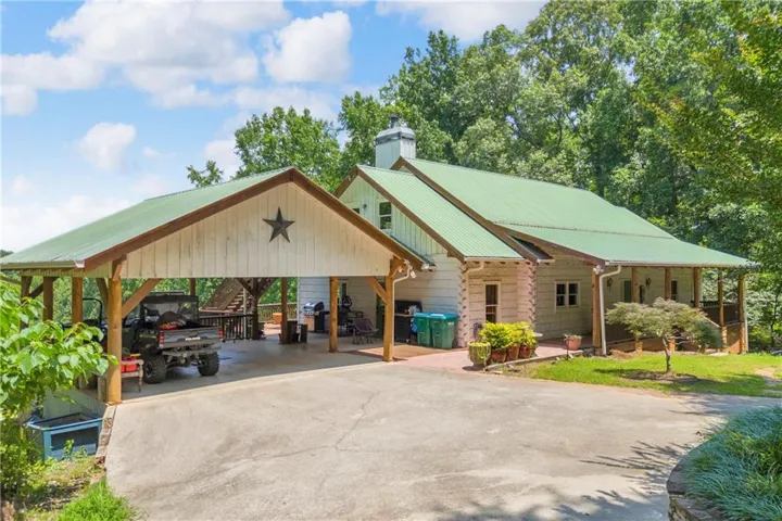 Exterior featuring a green metal roof, a wood-sided carport, and a covered porch