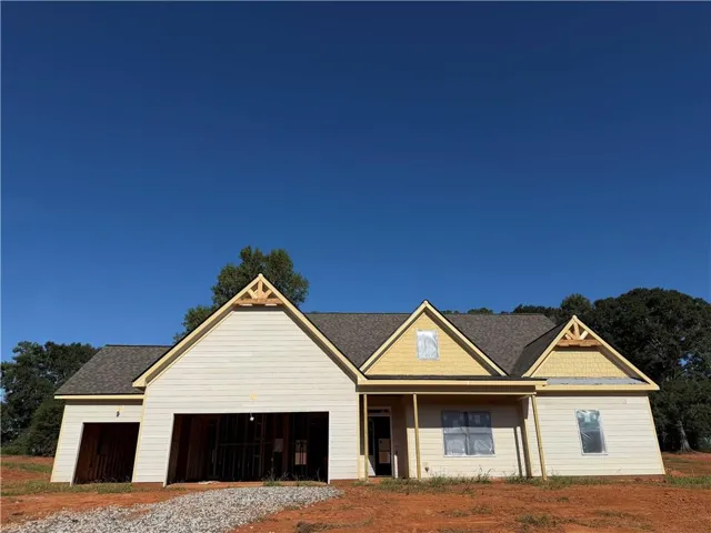 New construction residence featuring a multi-gabled roofline, partial siding, and an attached garage