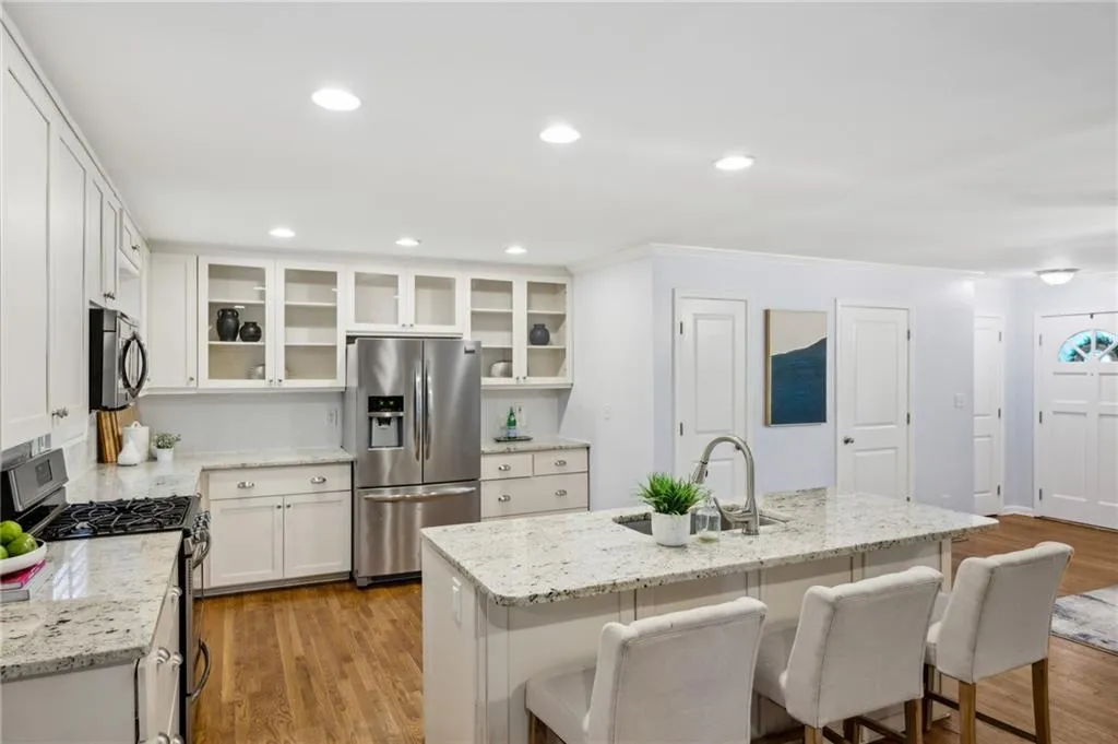 Renovated Kitchen with granite counters, large island, stainless appliances, and glass-front display cabinets