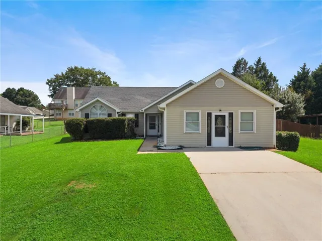 Exterior featuring a light-colored siding, gabled roofline, concrete driveway, and a front entry door with a storm door