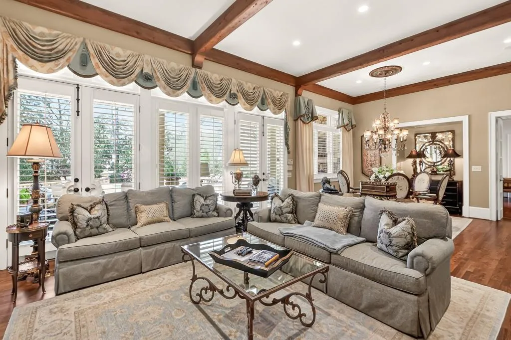 Large Family Room with floor to ceiling windows, heart pine ceiling beams, hardwood floors and french doors to veranda and pool