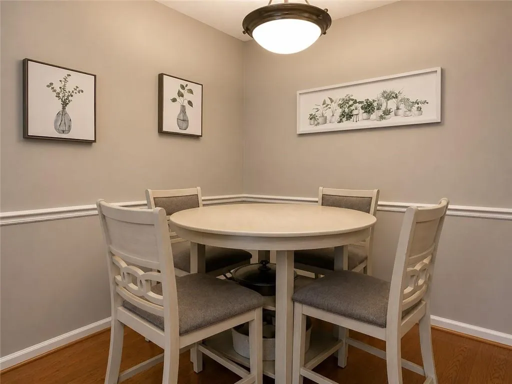 Corner dining area featuring neutral wall paint, white chair rail molding, and wood-finish flooring