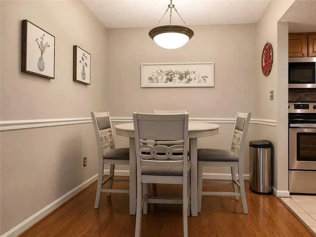 Dining space featuring wood-finish flooring, a tiered chandelier, and chair rail molding