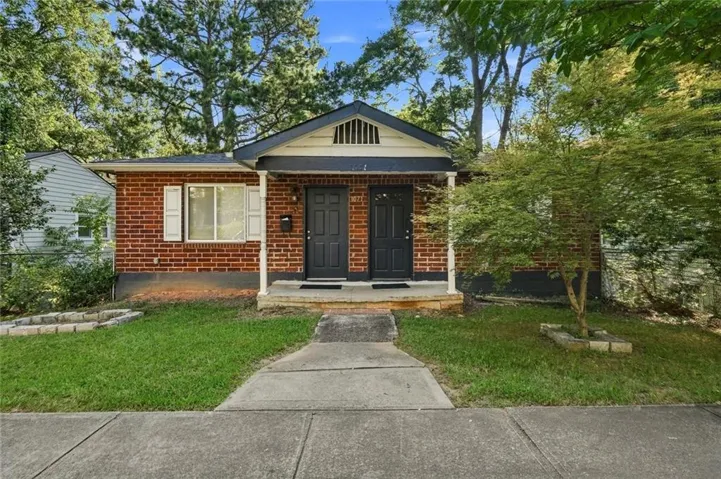 Red brick exterior with white trim, featuring a gable roofline and a covered porch entry