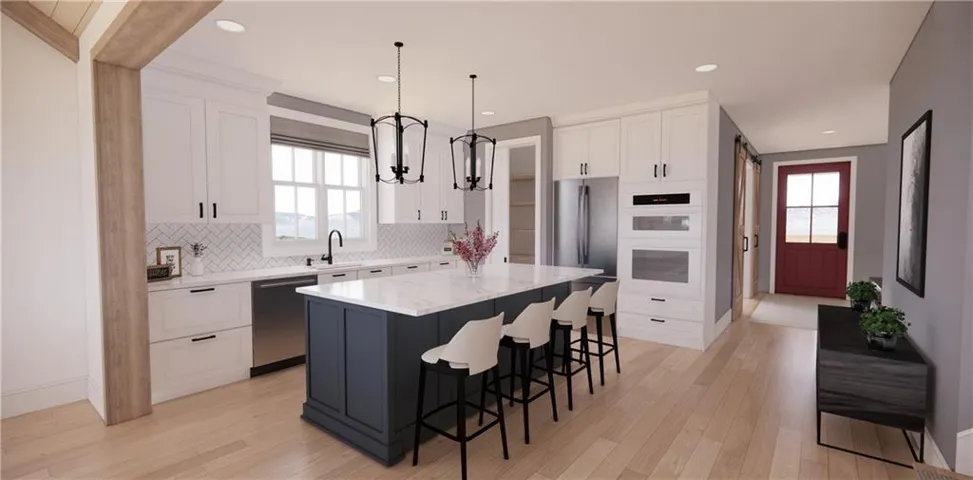 Kitchen featuring pendant lighting, a breakfast bar, white cabinetry, light stone counters, and a center island