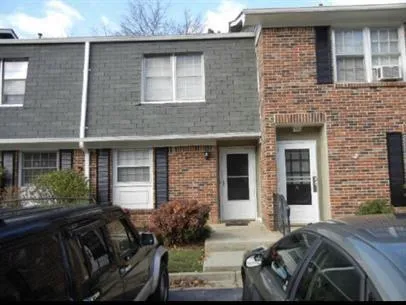 Brick and shingle exterior featuring multiple windows and a front entrance with a storm door