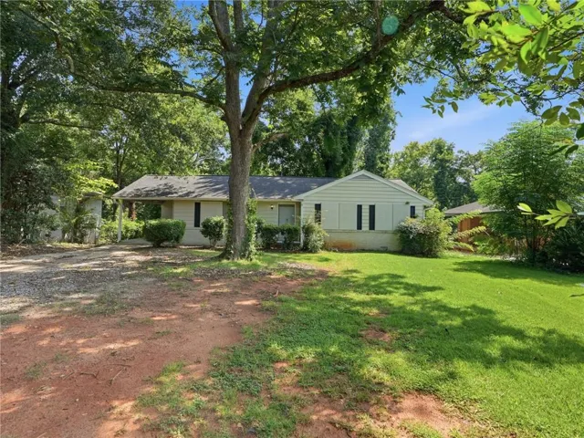 Single-story residence with a covered porch, light-colored siding, dark shutters, and a sloped roof