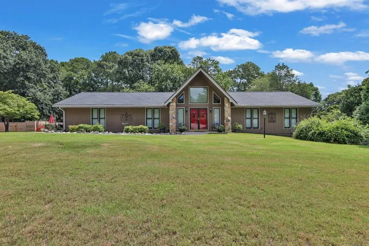 Contemporary ranch-style residence featuring a prominent gabled entry with stacked stone accents and dual red entry doors