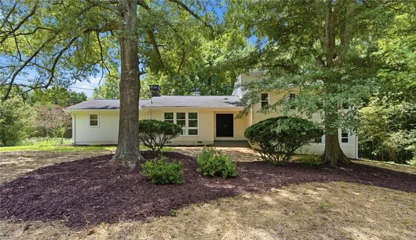 Cream-colored exterior featuring a black front door, multiple windows, and a shingle roof