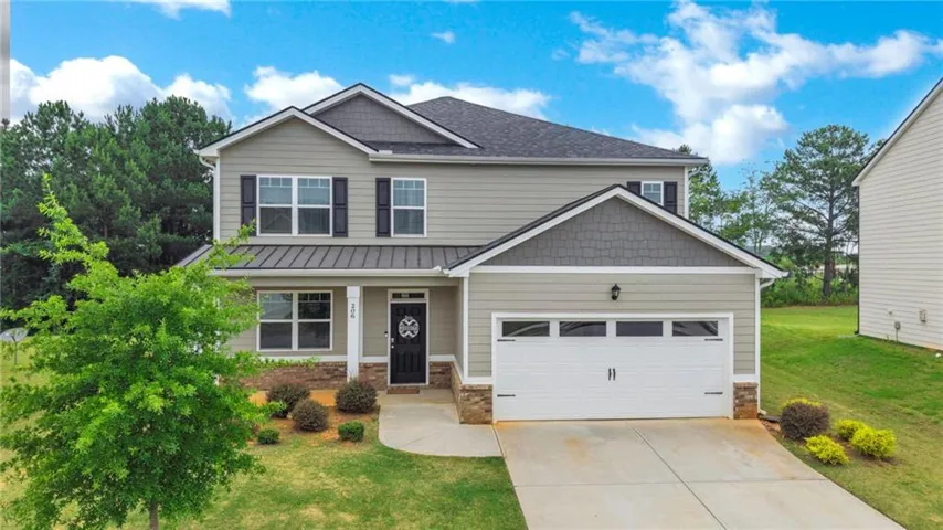 Two-story residence featuring light gray siding, dark shutters, and a two-car garage