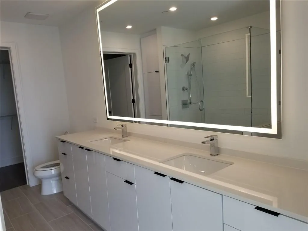 Bathroom featuring a shower with door, vanity, and toilet