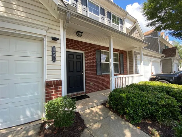 Brick and siding exterior with a covered porch, white garage door, and dark front door
