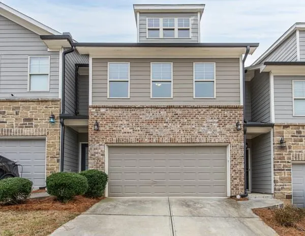 View of front of home featuring concrete driveway, an attached garage, and brick siding